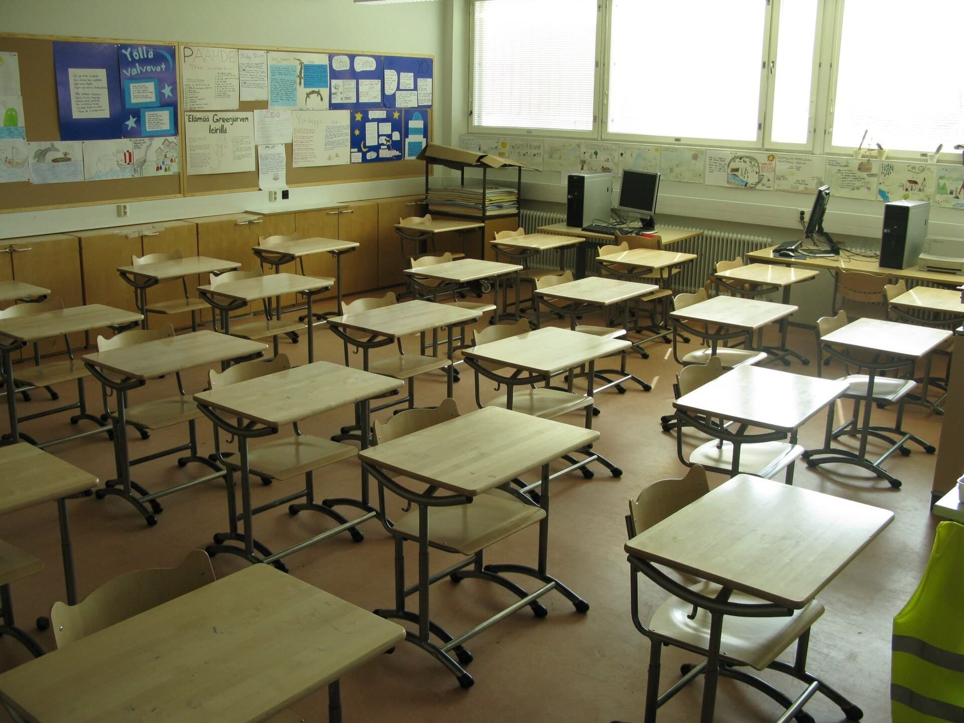 Rows of empty desks in a school classroom.